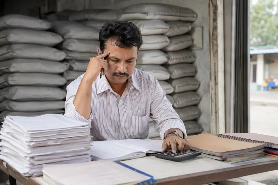 A Cement channel partner working out incentives by hand with paper circulars and registers