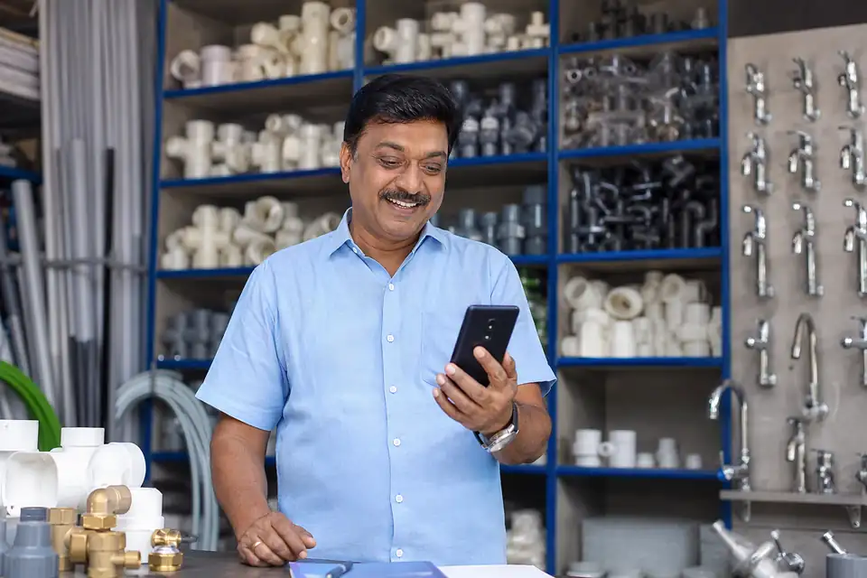 A plumber at a bathroom site scanning a QR code on a CPVC fitting pack with his phone