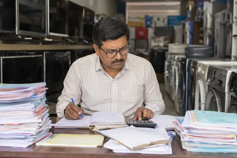 An appliance dealer working through scheme papers in his showroom