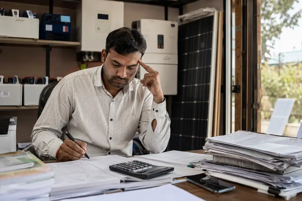 A Solar & Power Backup channel partner working out incentives by hand with paper circulars and registers